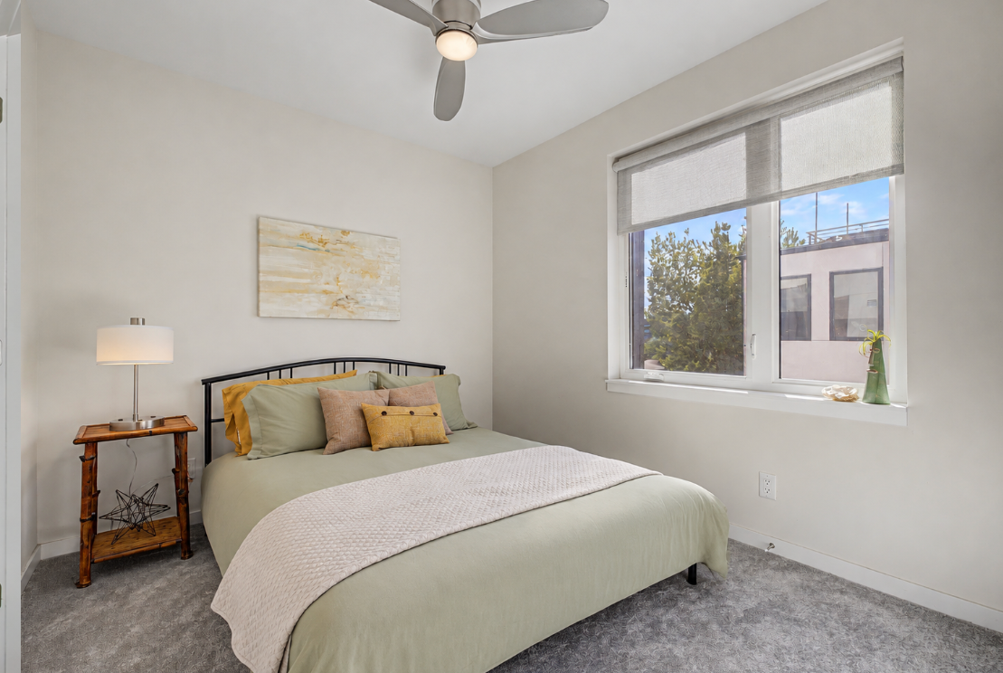 Bedroom with pale green bedding and a large window