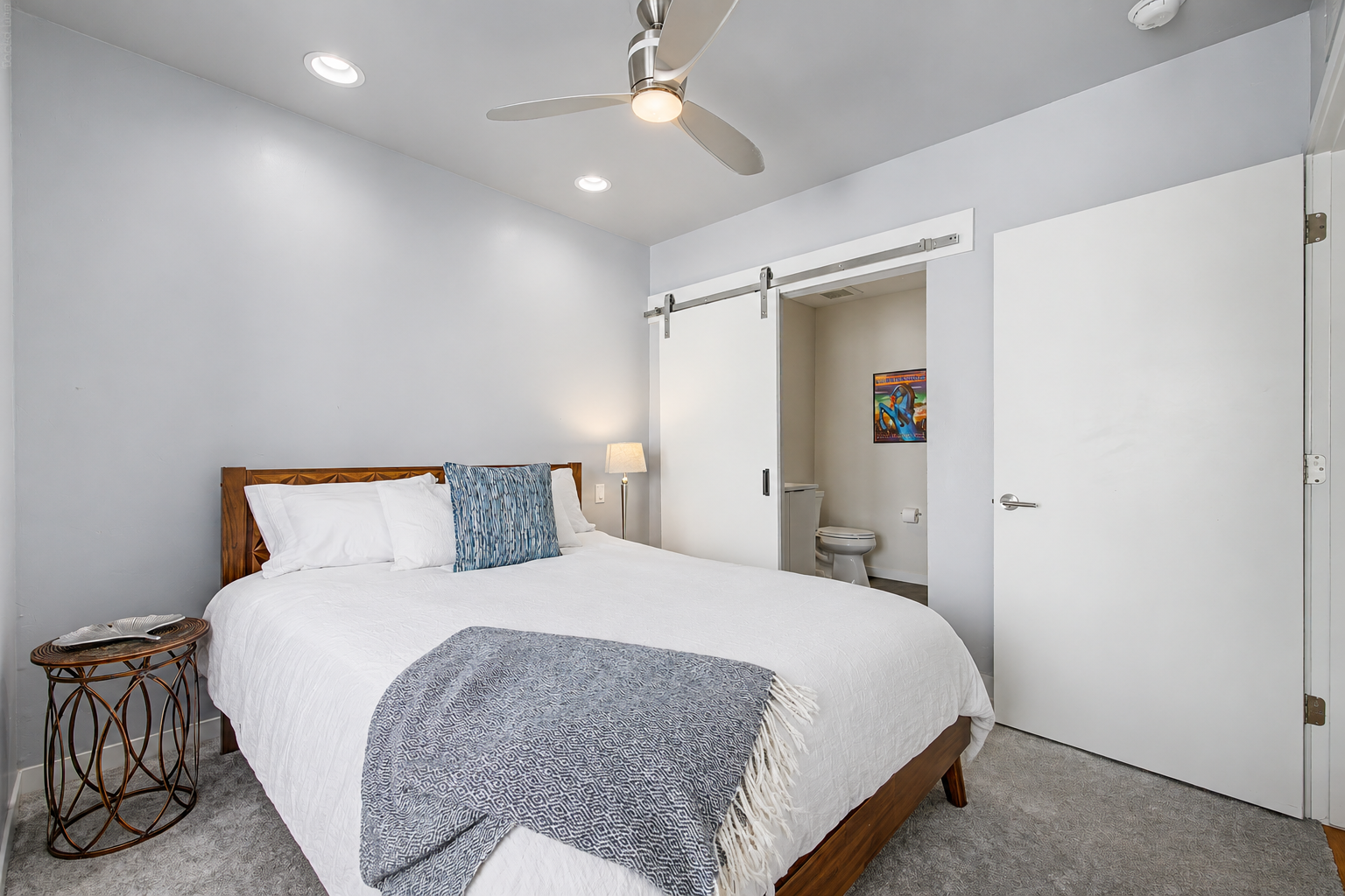 Primary bedroom with white bedding and sliding bathroom door